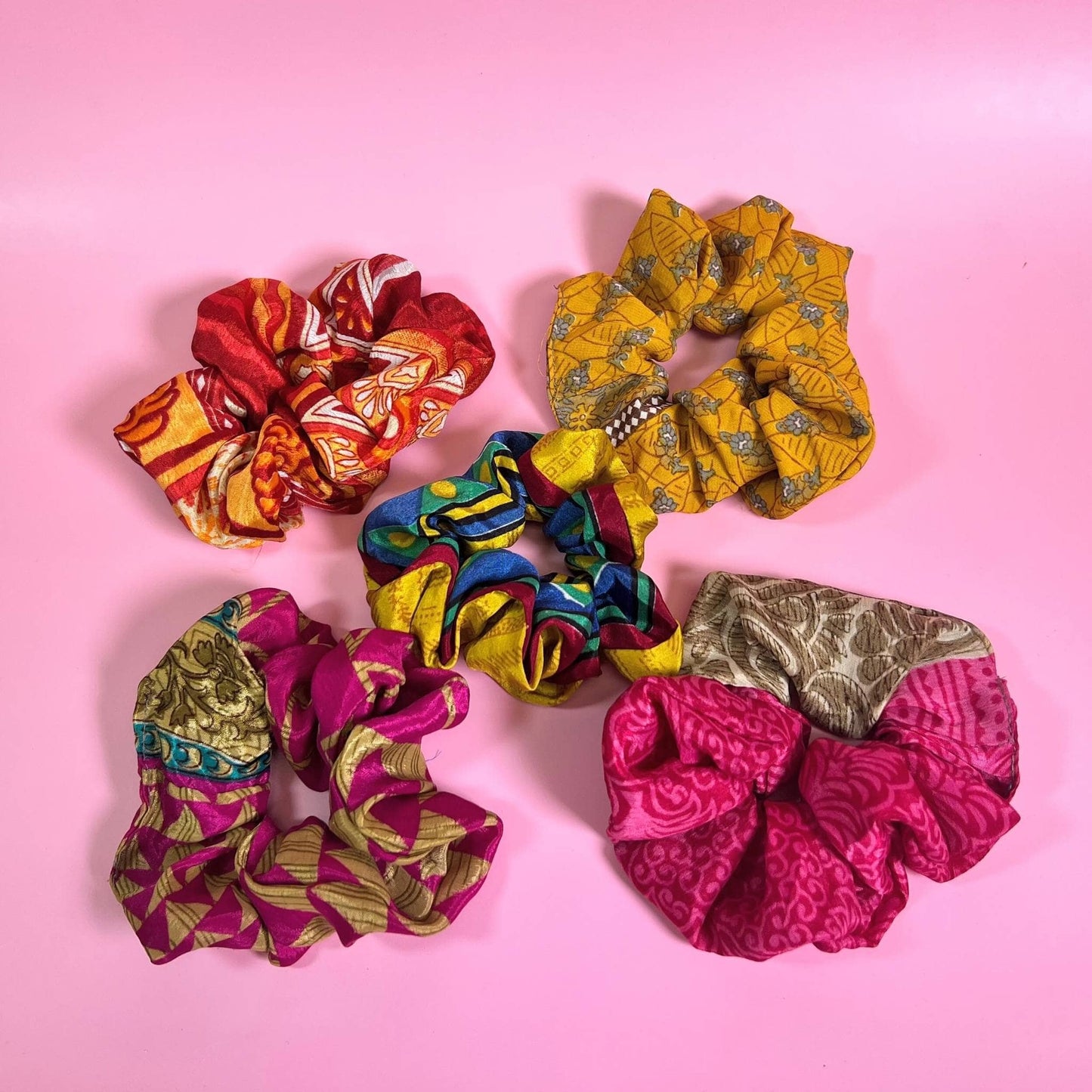 5 sari silk scrunchies on a pink backdrop.