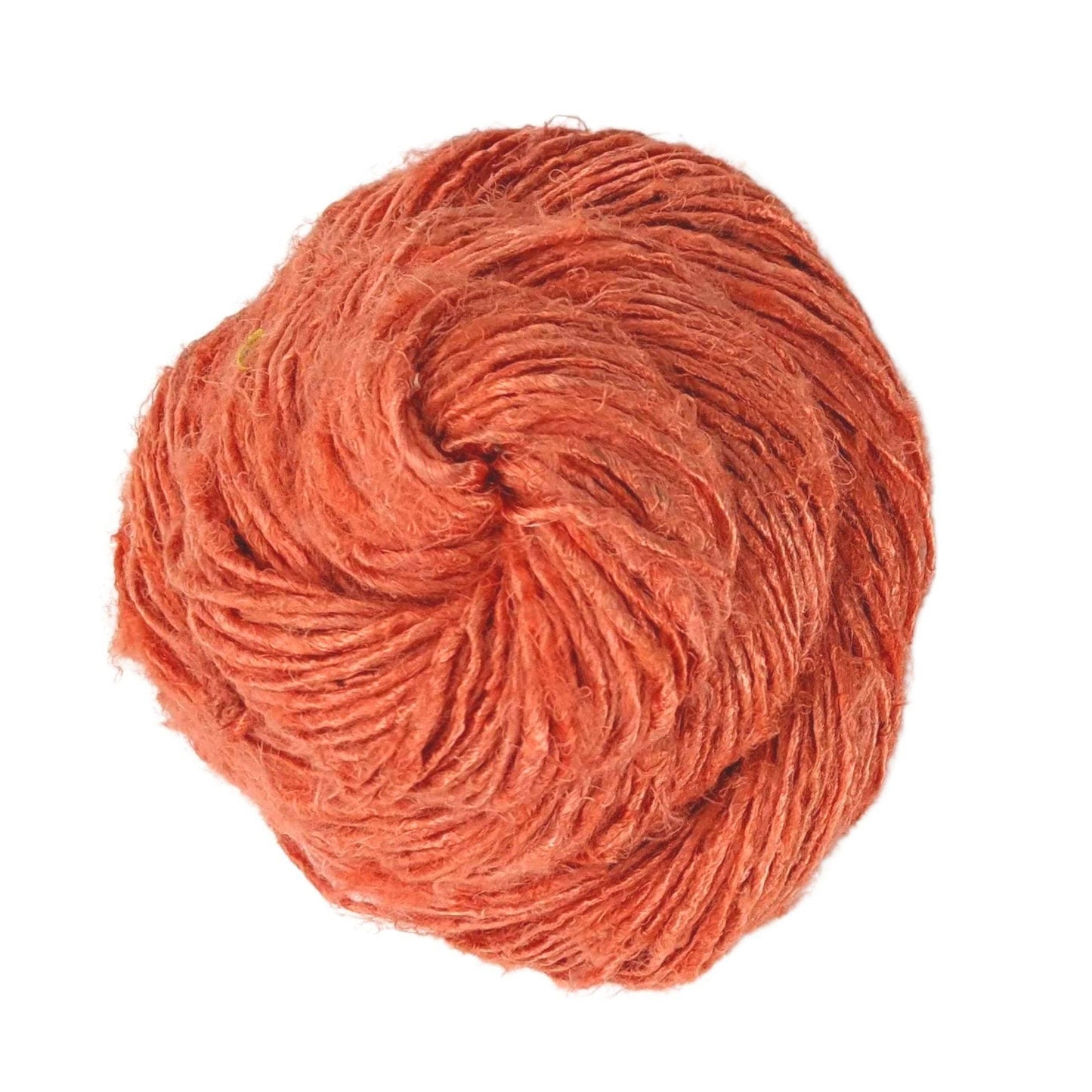 Top view of skein of dusty rose banana fiber yarn curled into a birds nest shape in front of a white background.