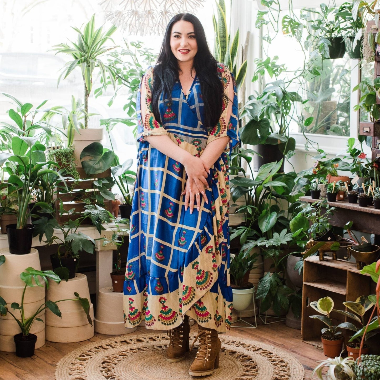 A Model wearing a Navy Blue Checker Pattern Zaria Wrap Dress in a Plant Shop.