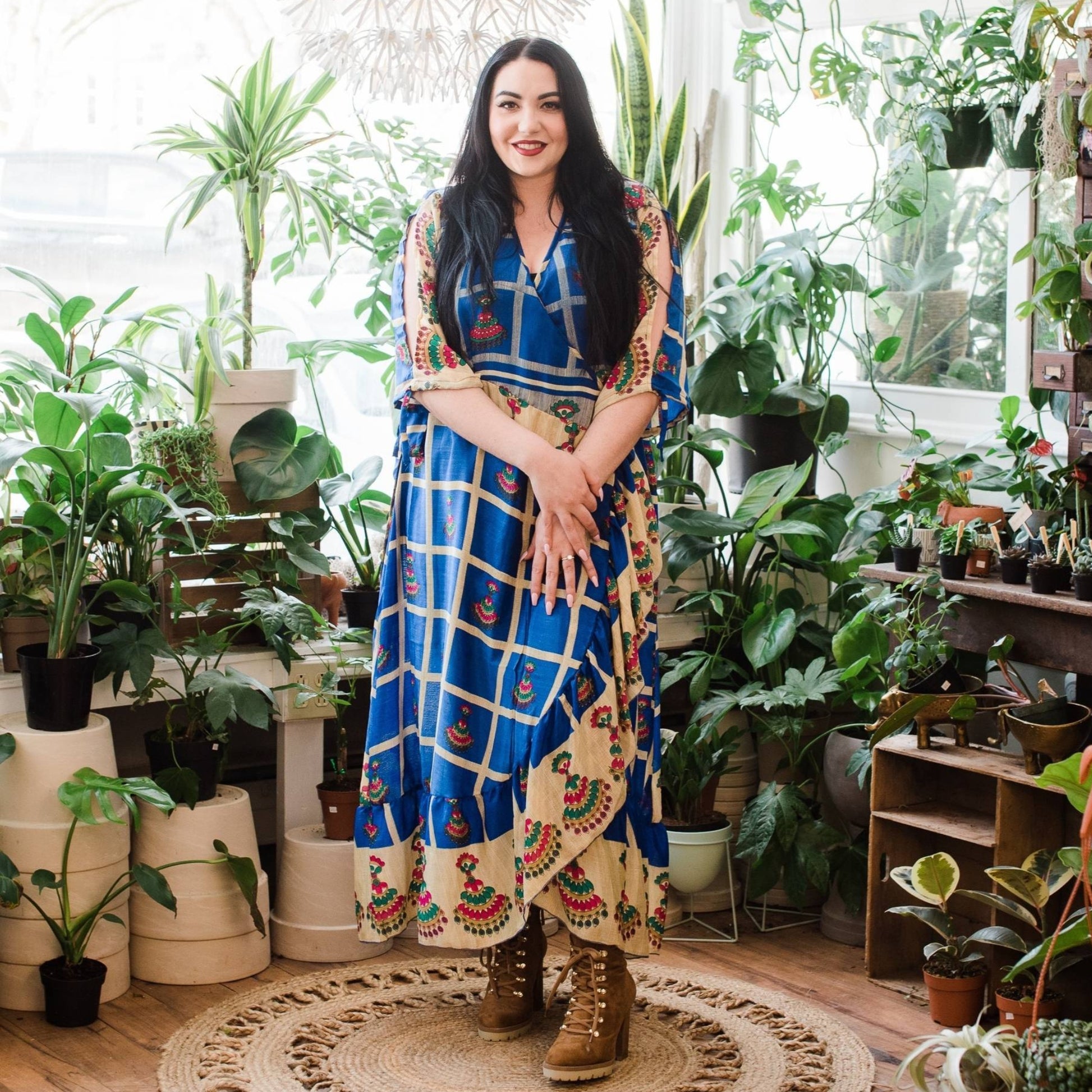 A Model wearing a Navy Blue Checker Pattern Zaria Wrap Dress in a Plant Shop.