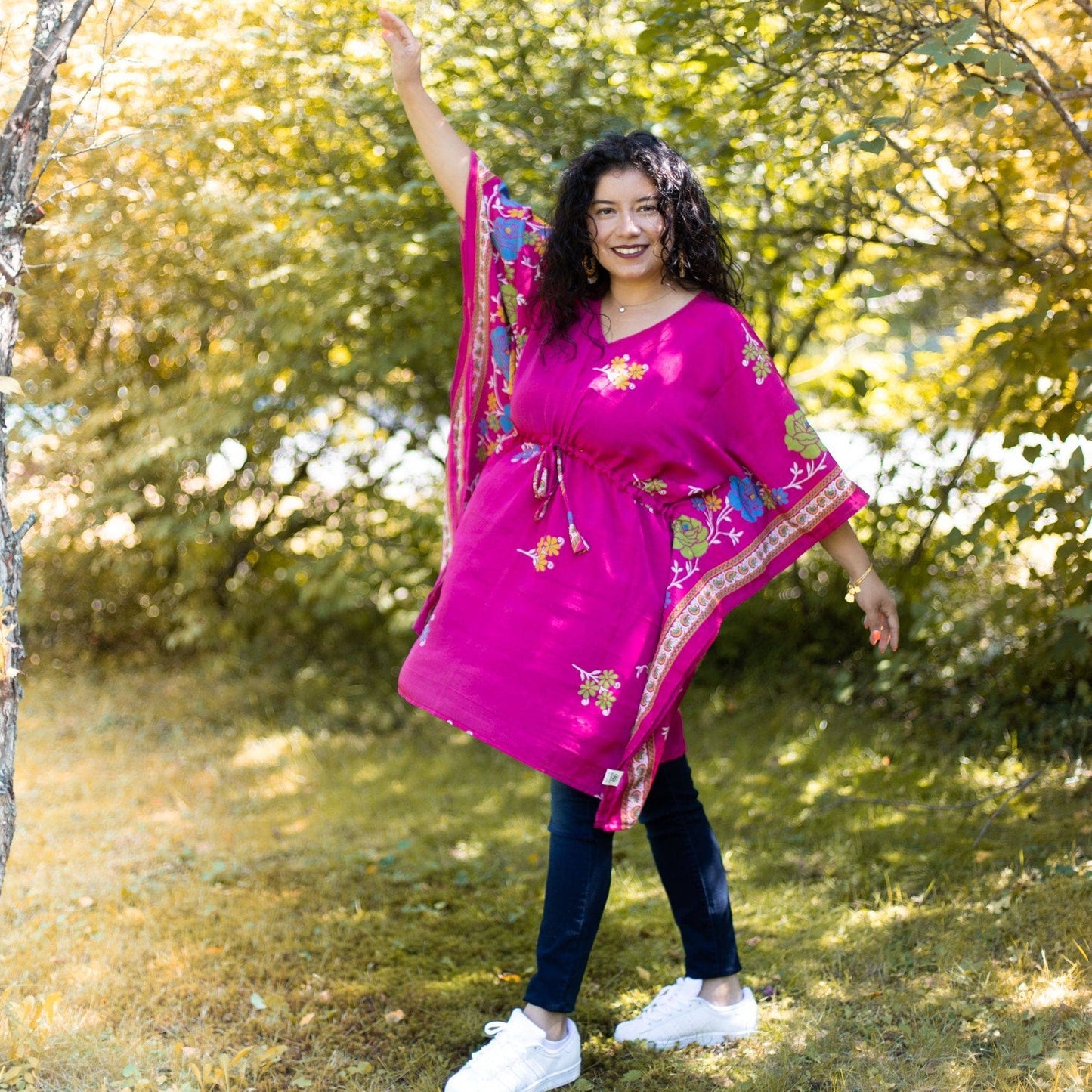 model wearing a pink aanya short kaftan dress while standing in front of some trees.