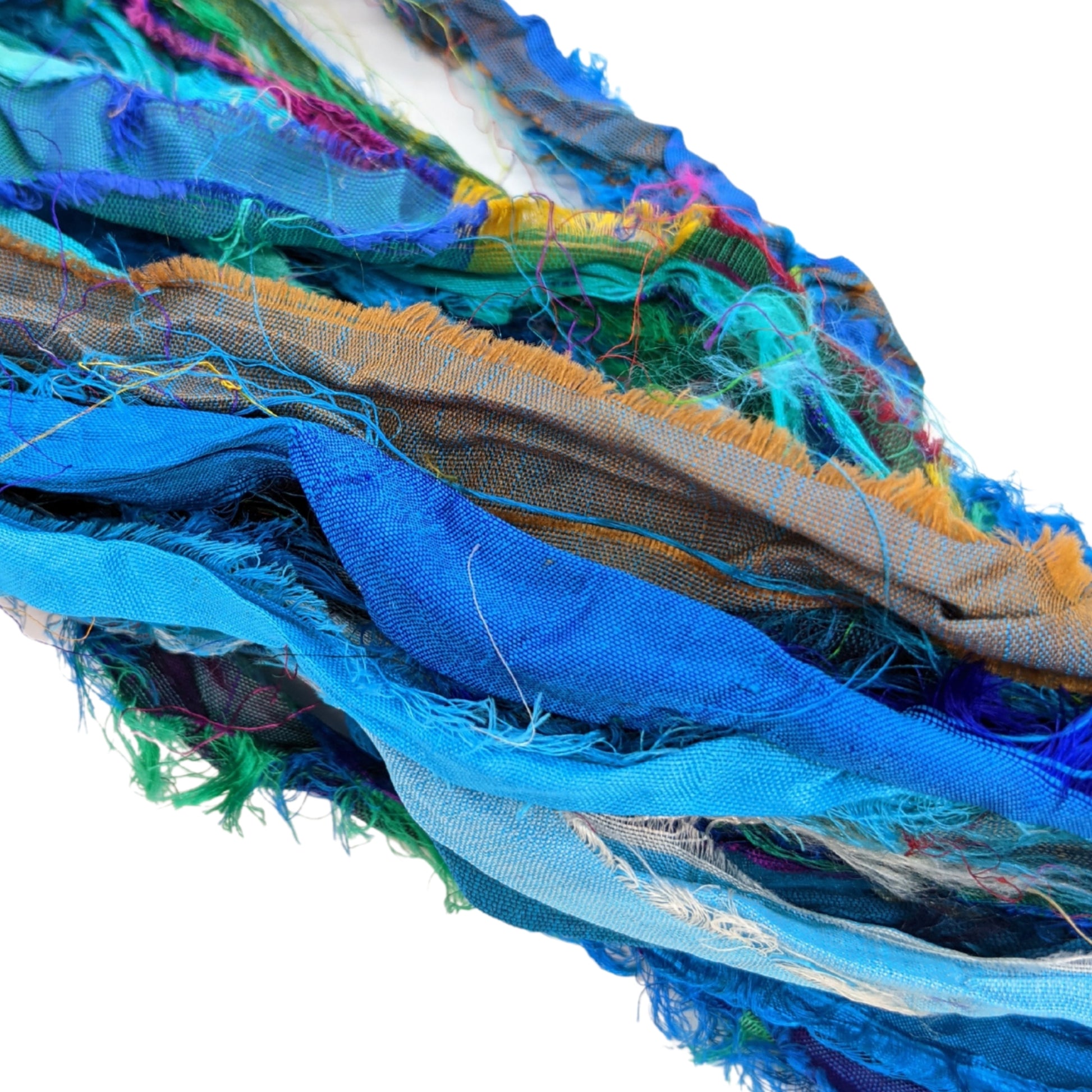 An up close view of Turquoise Sari Silk Ribbon laying out on a white background. This ribbon include vibrant sky and ocean blues, as well as some rich yellows and greens mixed in.