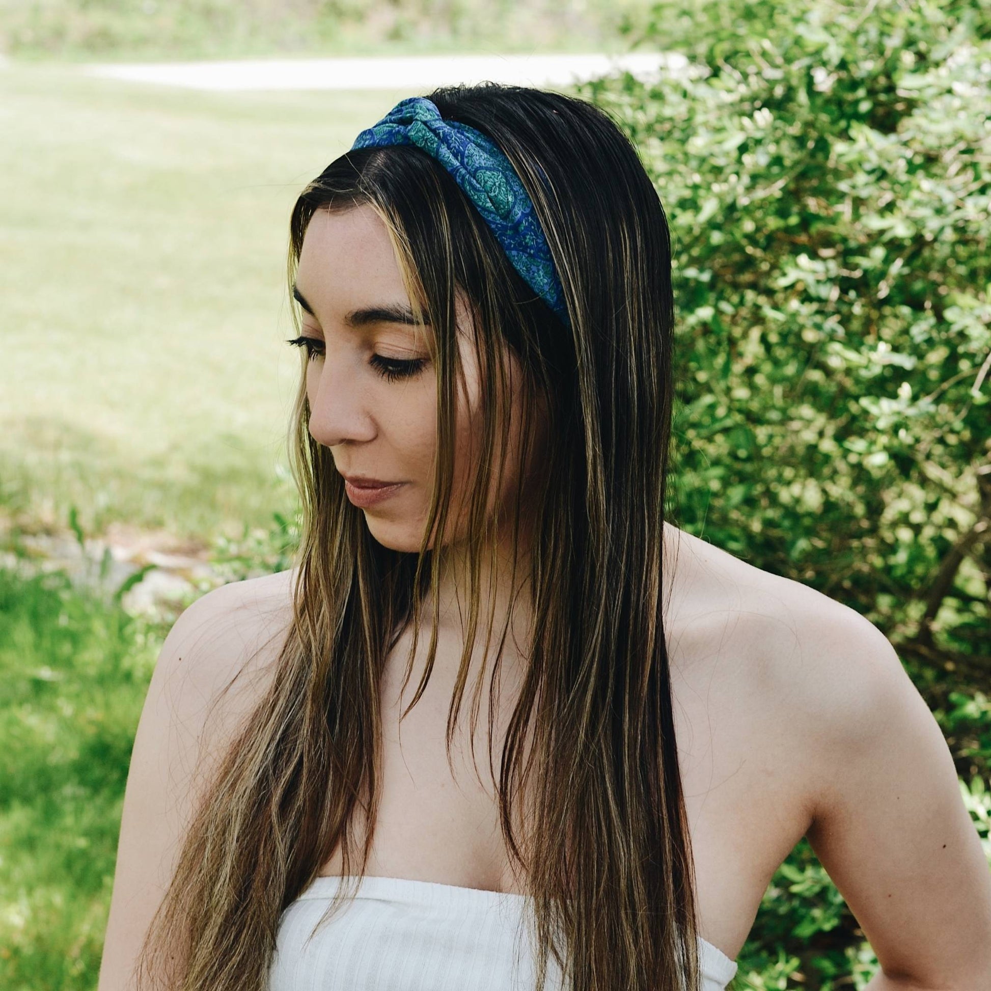 Model is wearing a blue kameela knot headband while standing outside.