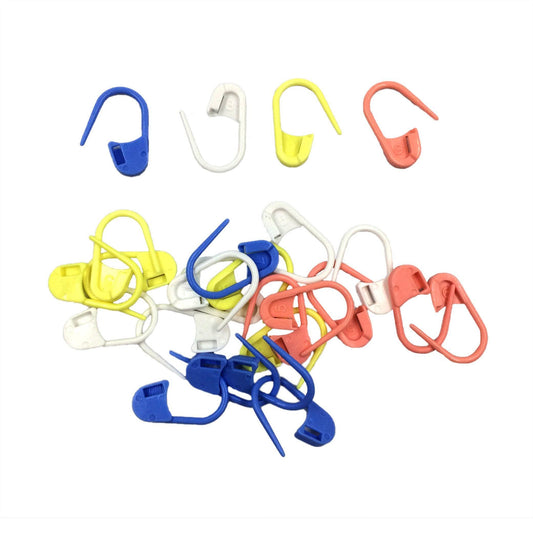 Pink, blue, yellow, and white knit stitch markers strewn on a white background