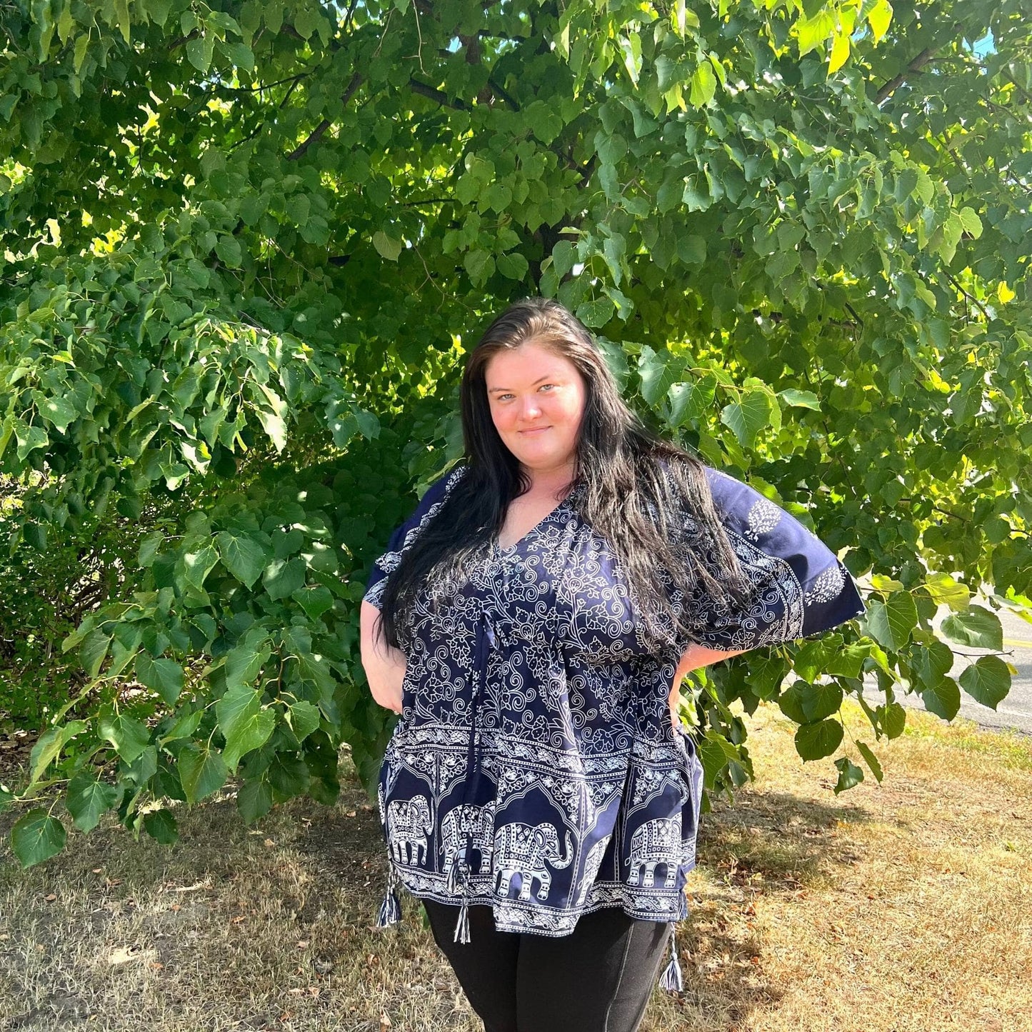 Model is wearing a navy Eloise Elephant kaftan in our goddess size while standing outside in front of a ree.