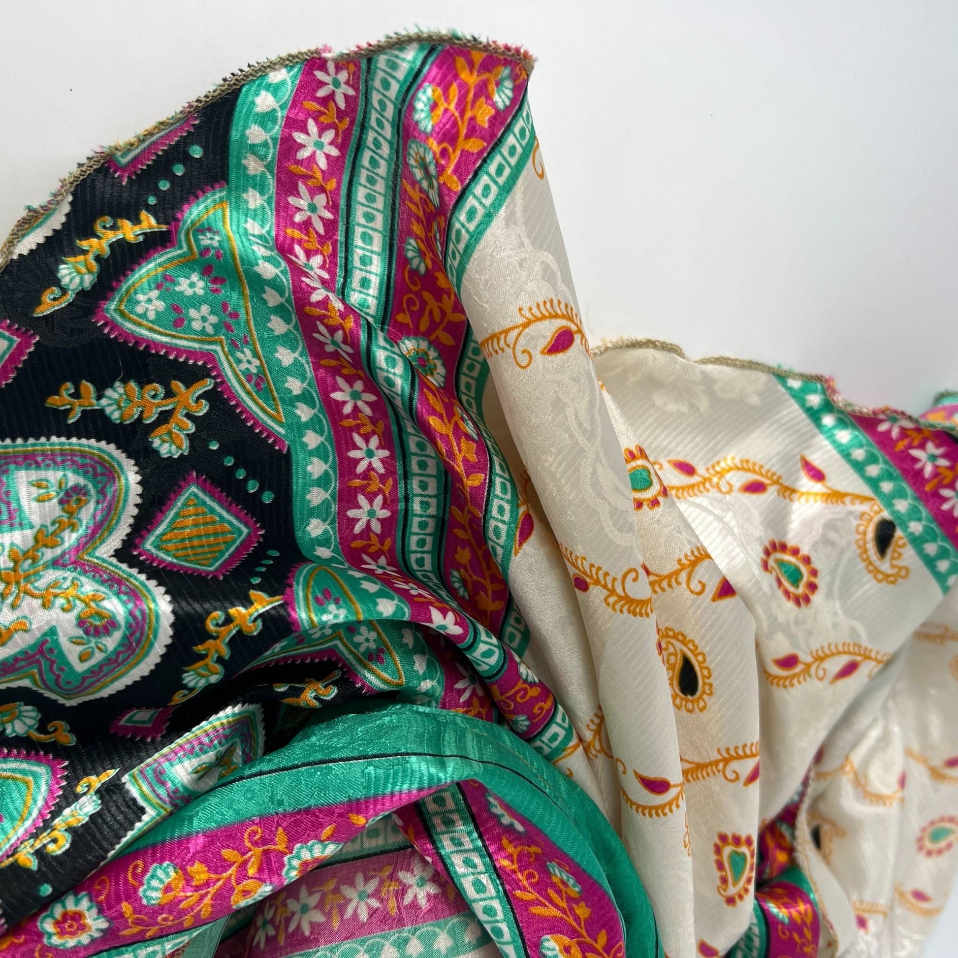 a white, green, black piece of sari silk fabric on a white backdrop.