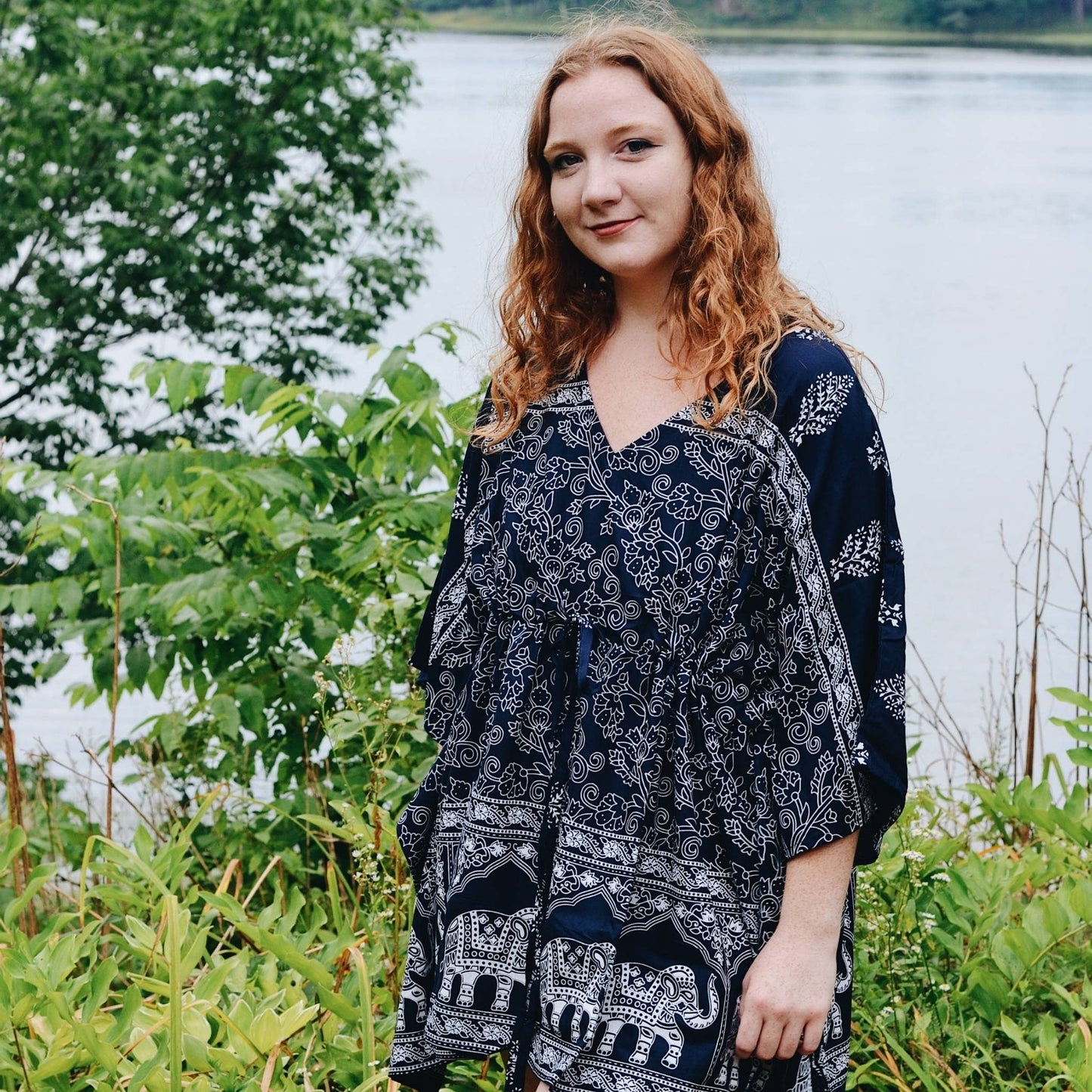 Model is standing outside in front of a lake wearing a Eloise Adjustable Elephant Kaftan