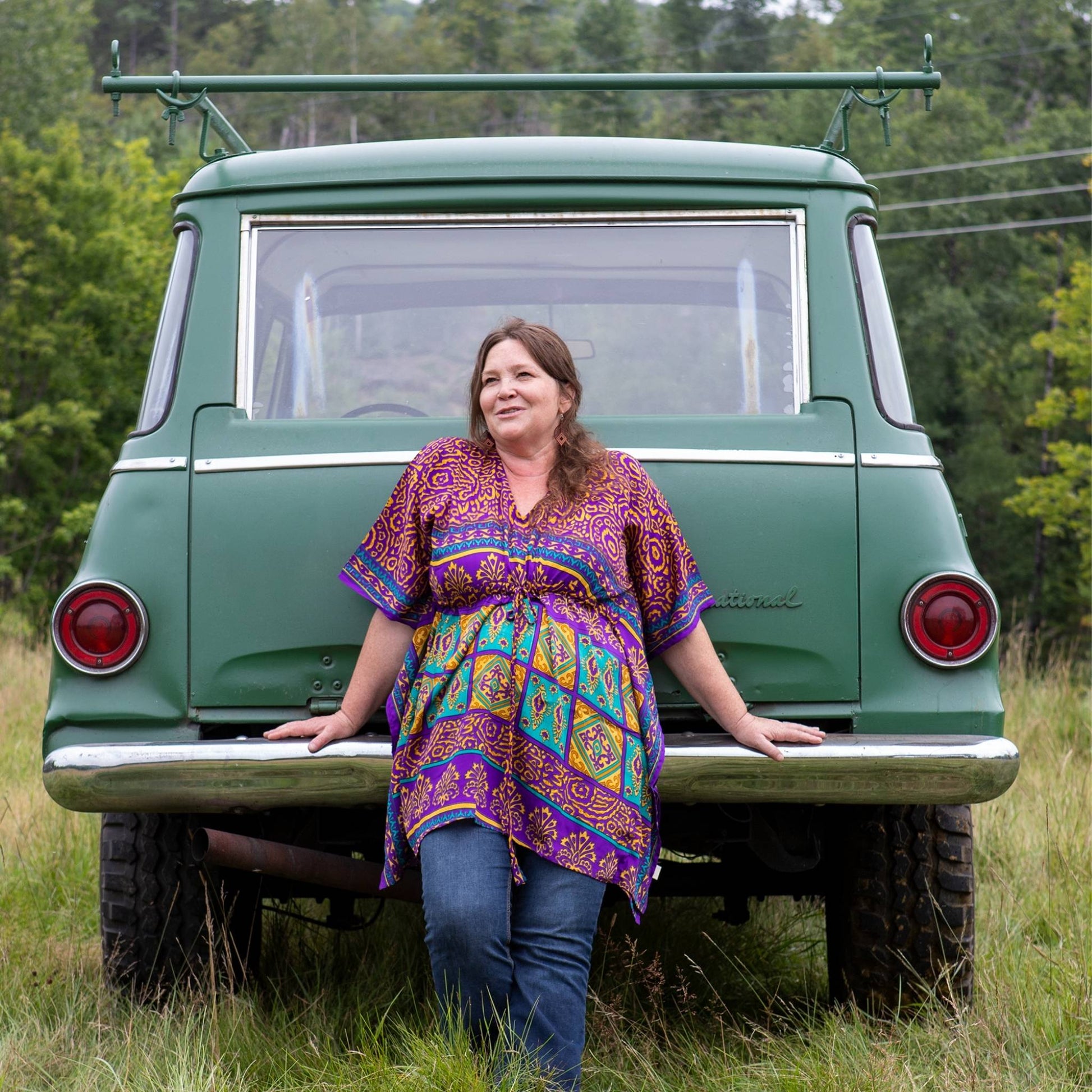 Model is leaning against a green car wearing a colorful goddess aanya short.