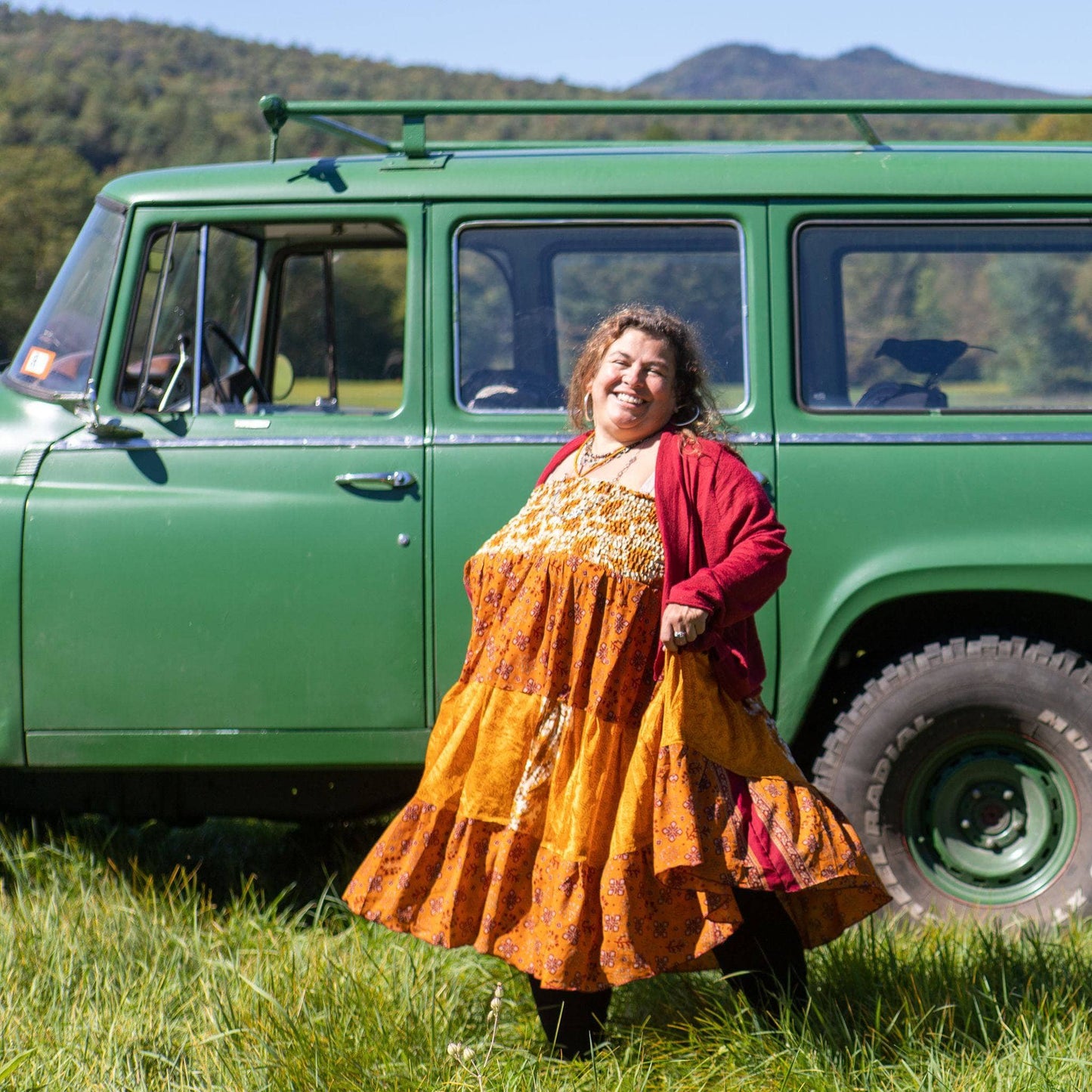 Model is in front of a green truck wearing an orange sedona as a dress.