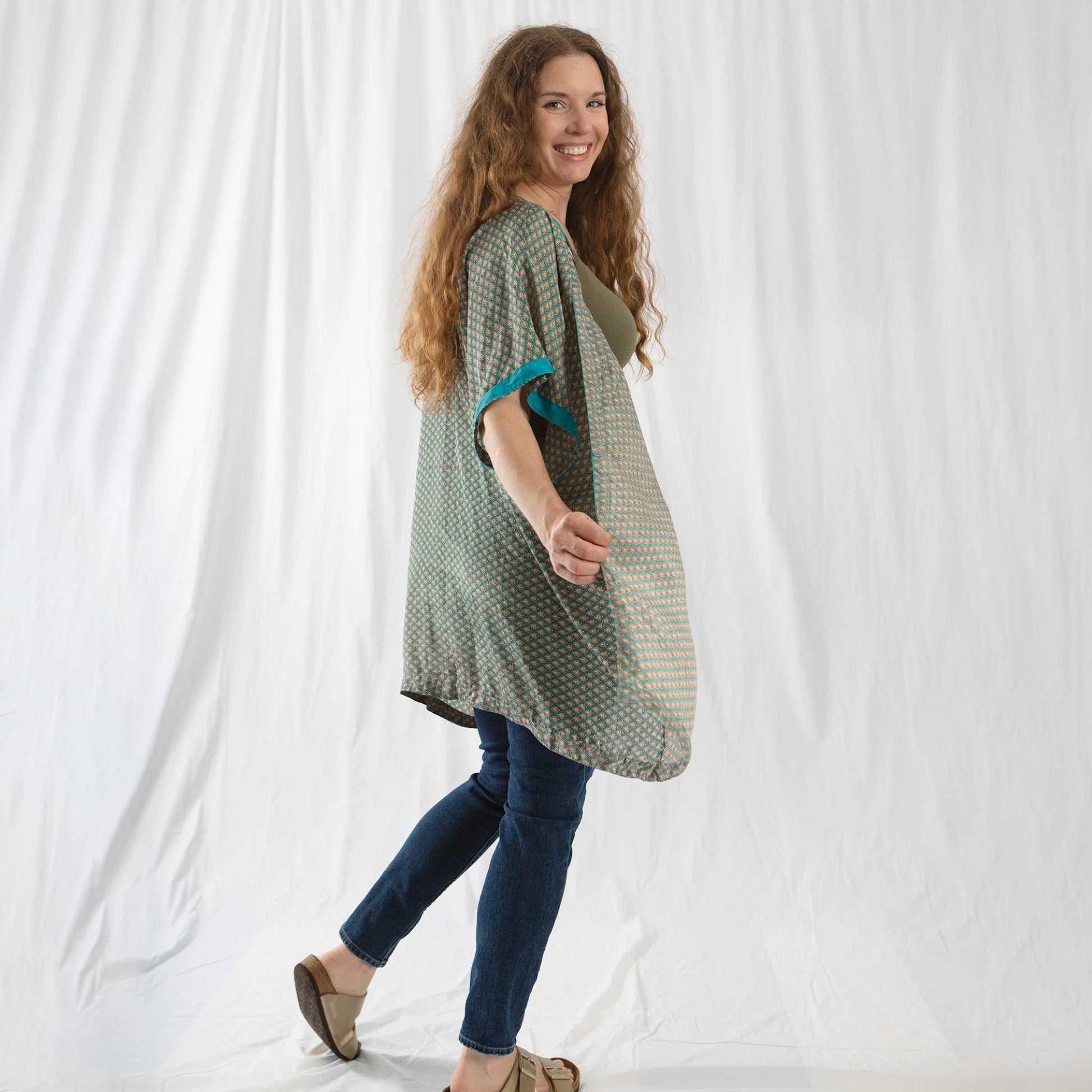 Model is in front of a white backdrop wearing a green amara duster.
