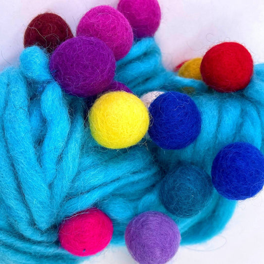 An up close view of the cyan blue felt ball wool yarn.  Showing the texture of the felt balls and the yarn. The felt balls are vibrant and rainbow in color.