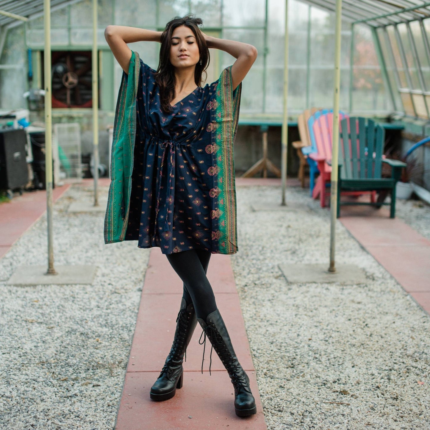 Model is wearing a blue and green aanya short while standing in a greenhouse.