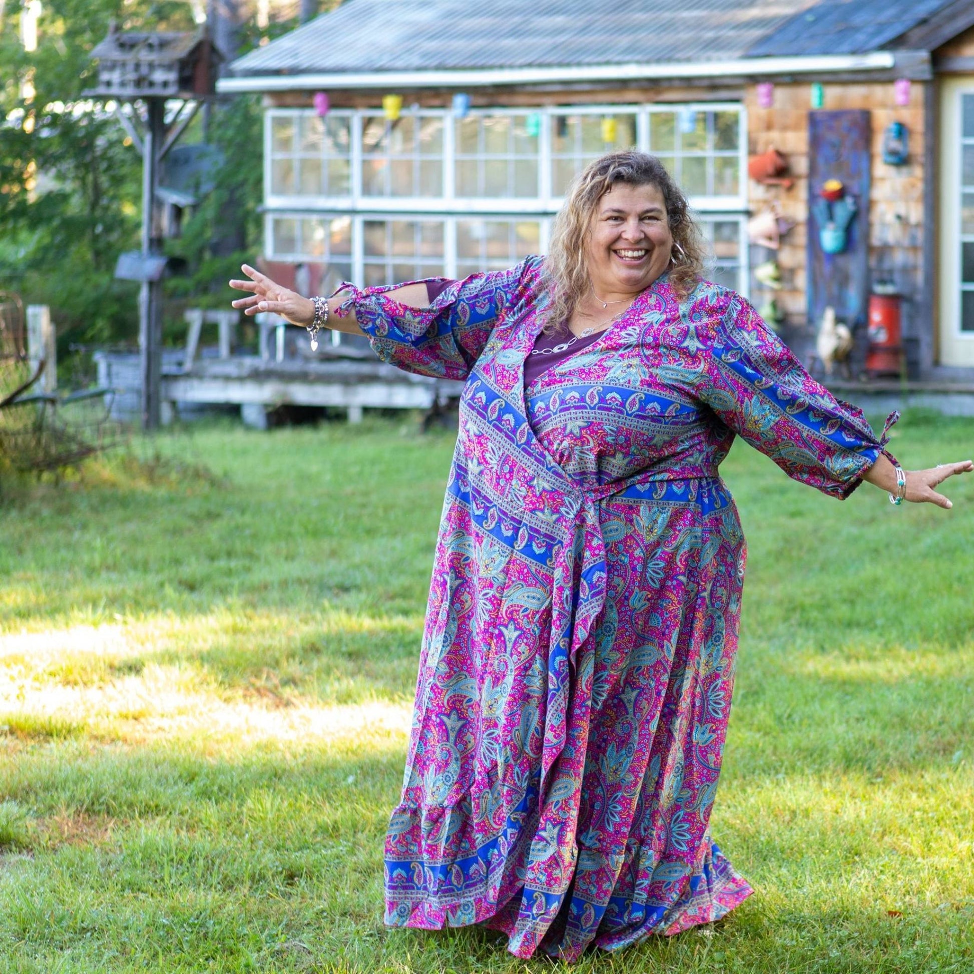Model had their hands stretched out by their side wearing a purple and blue Zaria Wrap dress.
