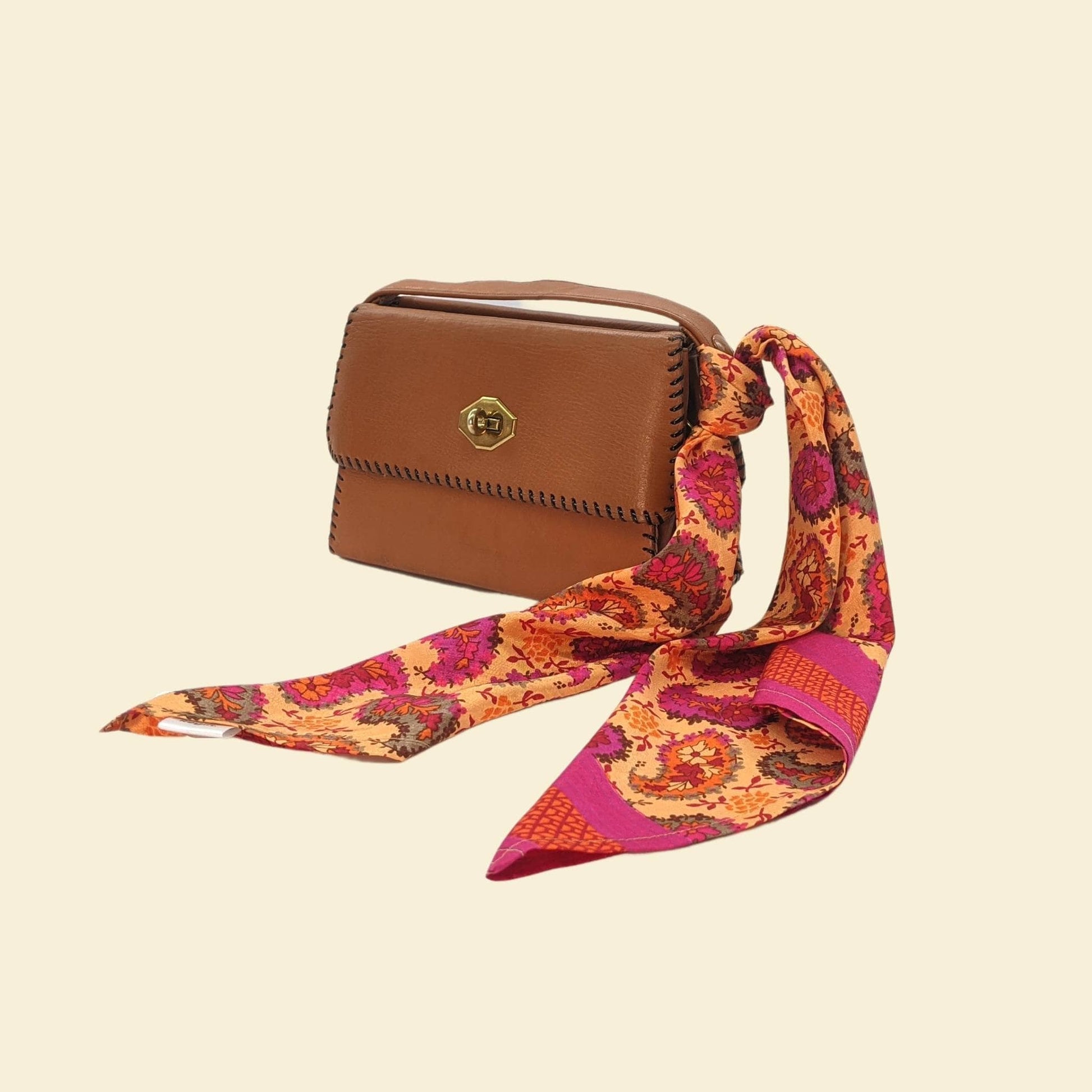 Pink and orange furoshiki is tied on a brown purse