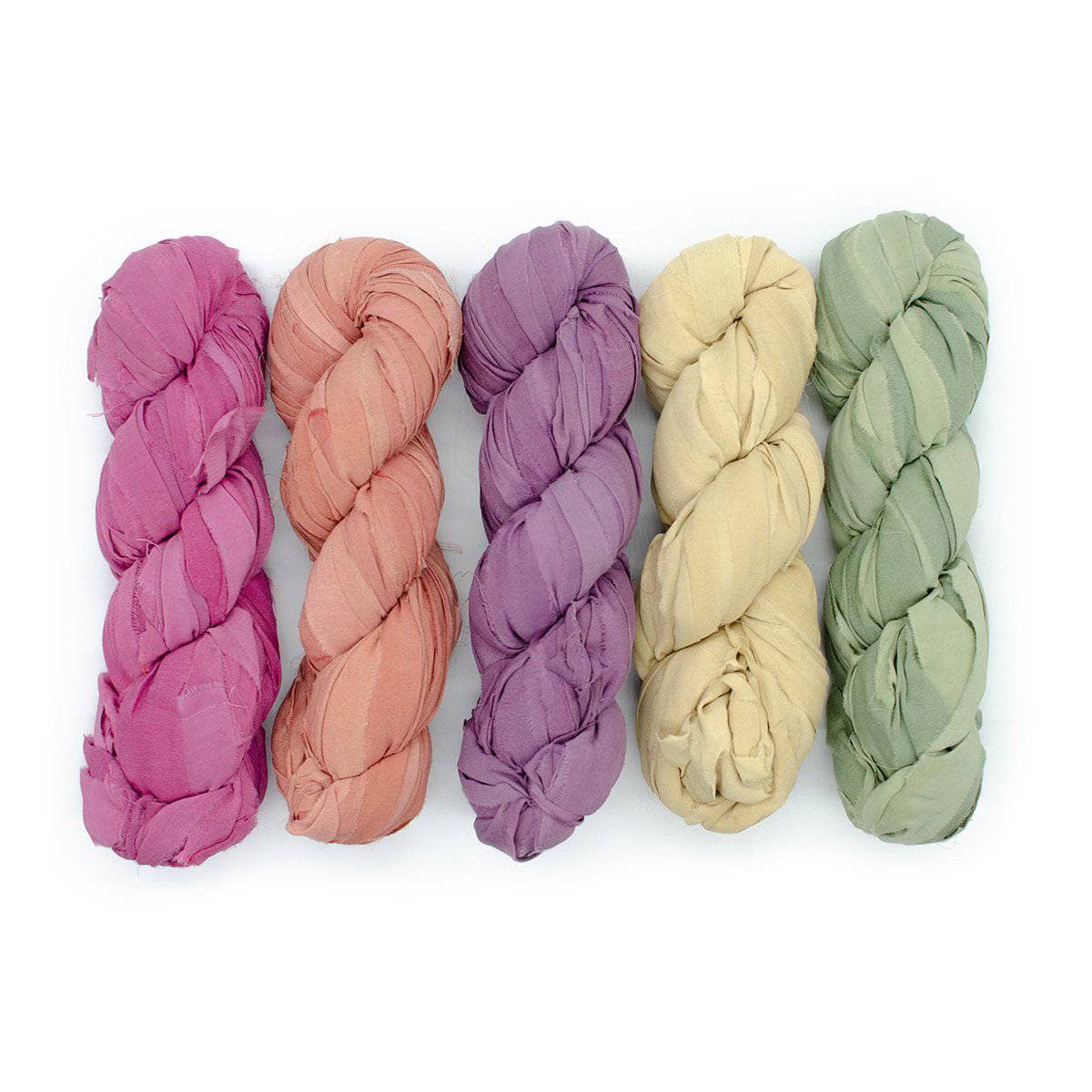 Chiffon Ribbon yarn is the colorway Vintage Chic on a white background. These colors are light blush pink, pea green, light yellow, orange and purple