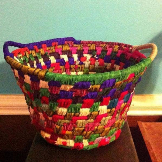 Yarn Wrapped Rope Basket in Tibet Jewels (multicolored) against a blue wall