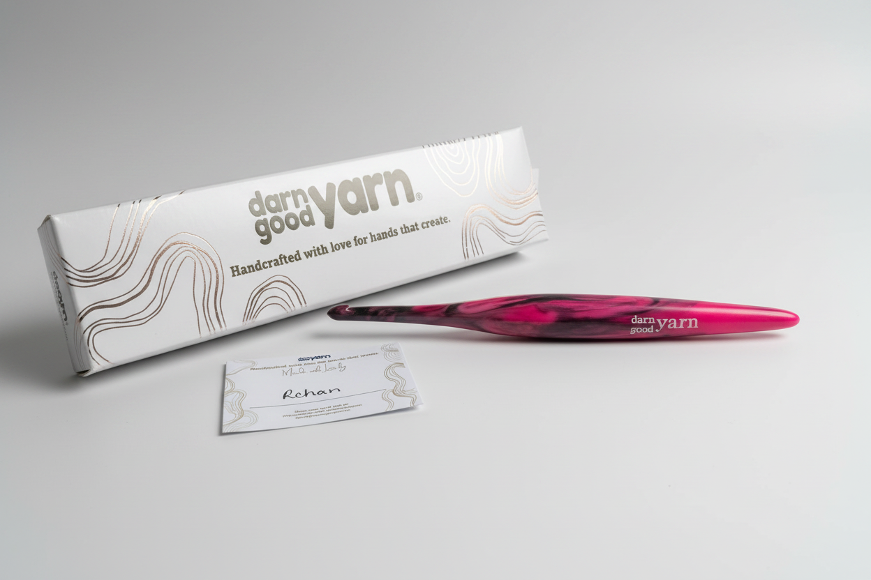 Pink crochet hook with 'darn good yarn' packaging on a white surface.