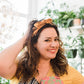 Model wearing yellow boho vintage sash accessory as a headband with a bow tied on top.