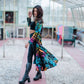Woman in a tie-dye duster walking through a greenhouse.