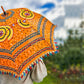 Model is holding an Embellished Parasol Umbrella with blurred trees in the background. 