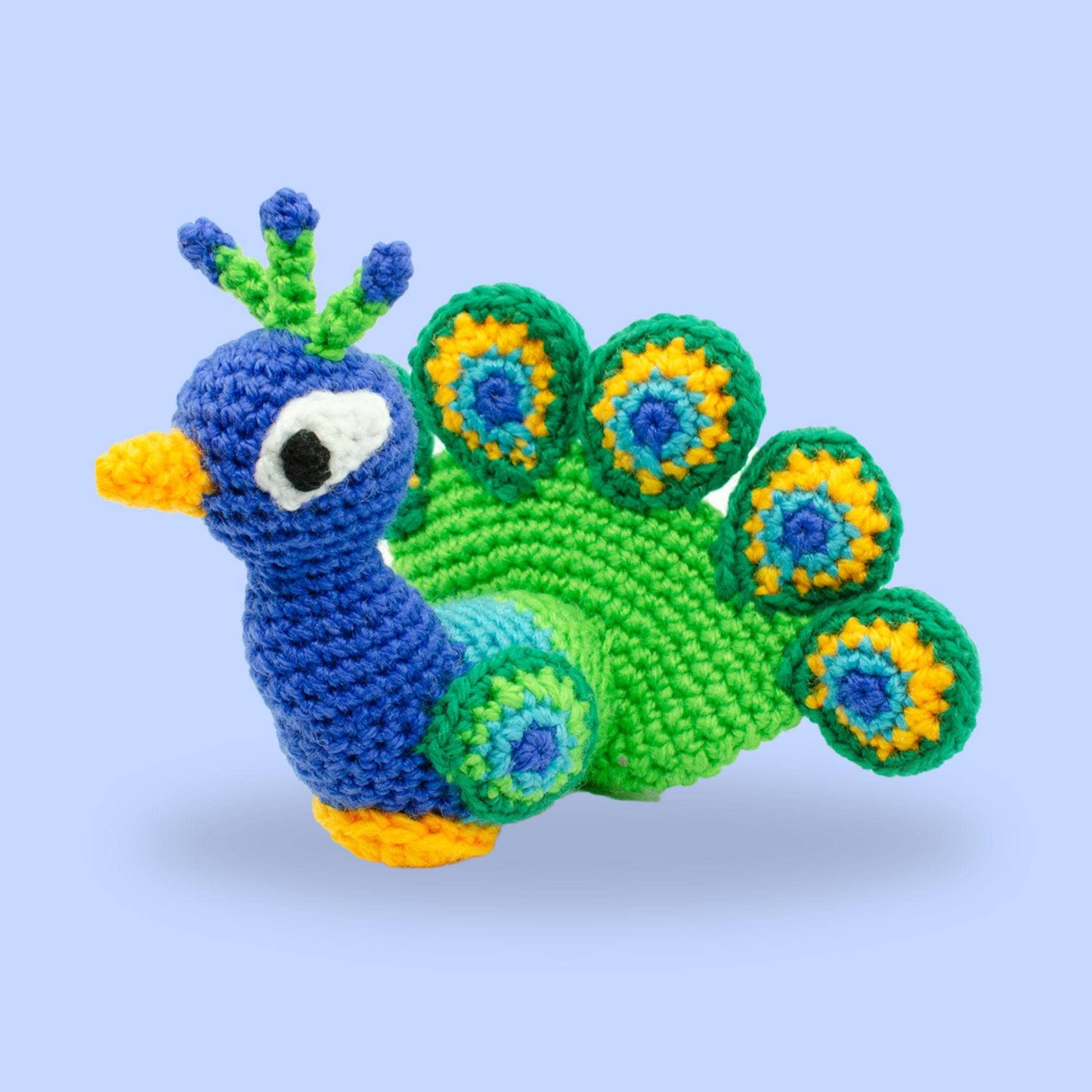 blue, green and yellow crochet peacock amigurumi on a purple background