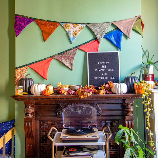 Bunting banner hangs over a fire place with pumpkins and message board saying bring on the pumpkin spice and everything nice. 