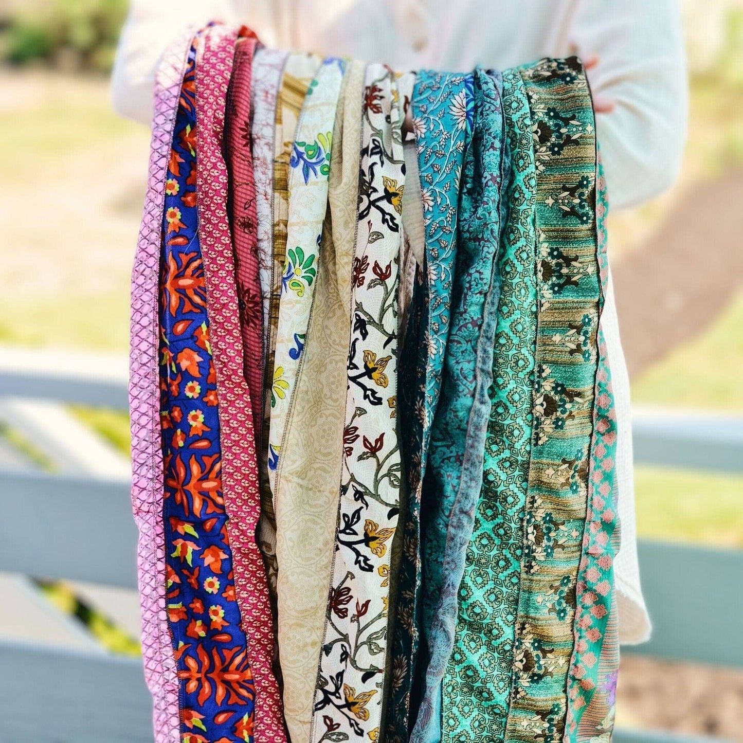 A person holding a multicolored scarf made from reclaimed sari fabric.