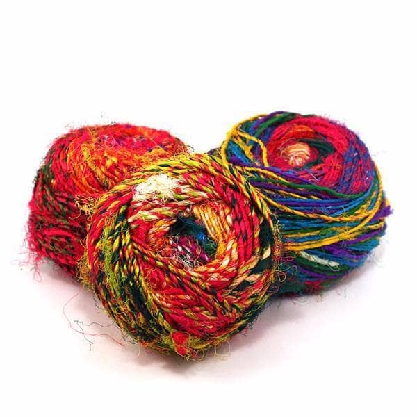 three cakes of yarn in different colors with a white background
