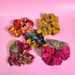 5 sari silk scrunchies on a pink backdrop. 