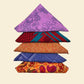 Five assorted furoshiki tied as triangles laying on a light yellow backdrop.