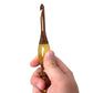 A hand holing a  wooden and resin crochet hooks.
