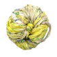 Tightly wrapped ball of multicolored fabric with yellow and green hues against a white background.