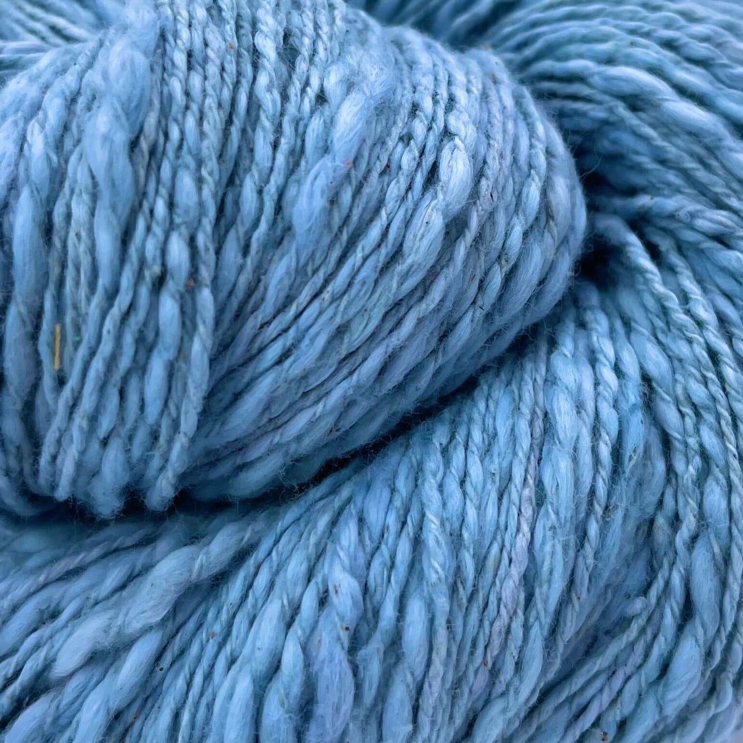 A close up of a skein of light blue cotton yarn on a white background