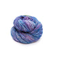 Lace weight silk yarn in color way in Tidal Pool (blue and purple) in front of white background.