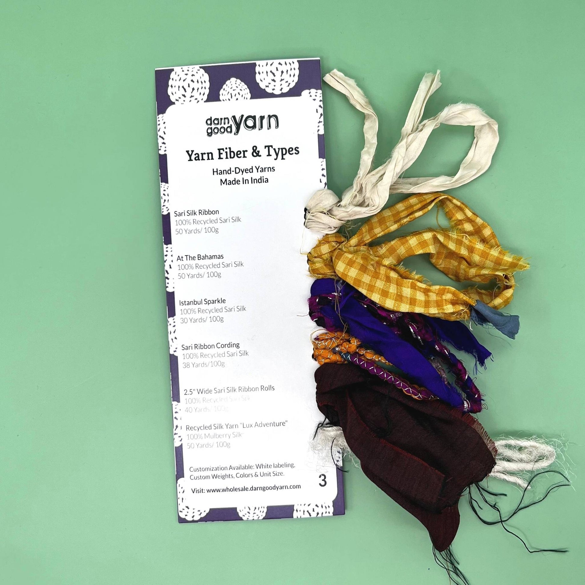 Yarn fiber and type sample cards on a green backdrop. 