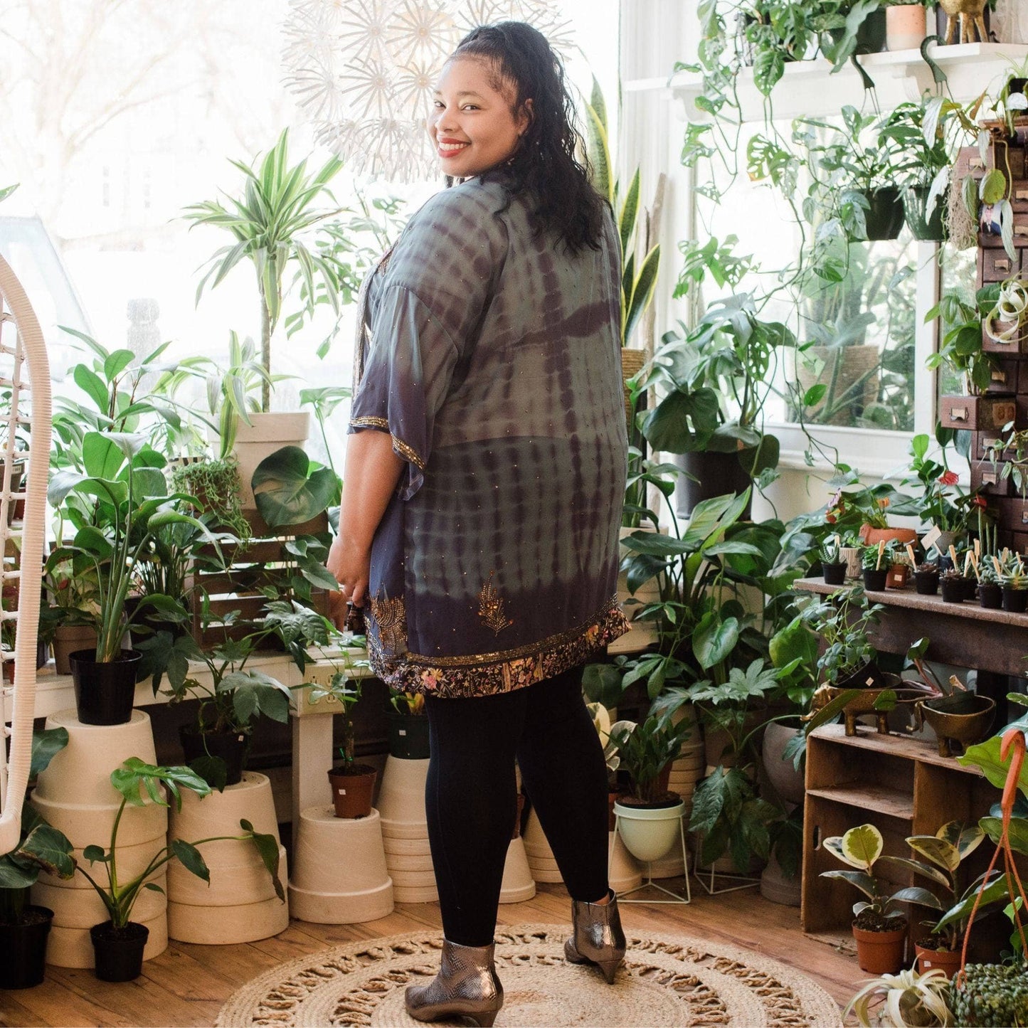 Plus size model is wearing a dark blue tie dye sophia silk duster with potted plants in the background. 