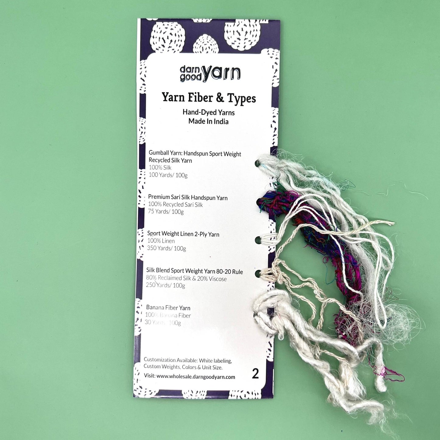 Yarn fiber and type sample cards on a green backdrop. 