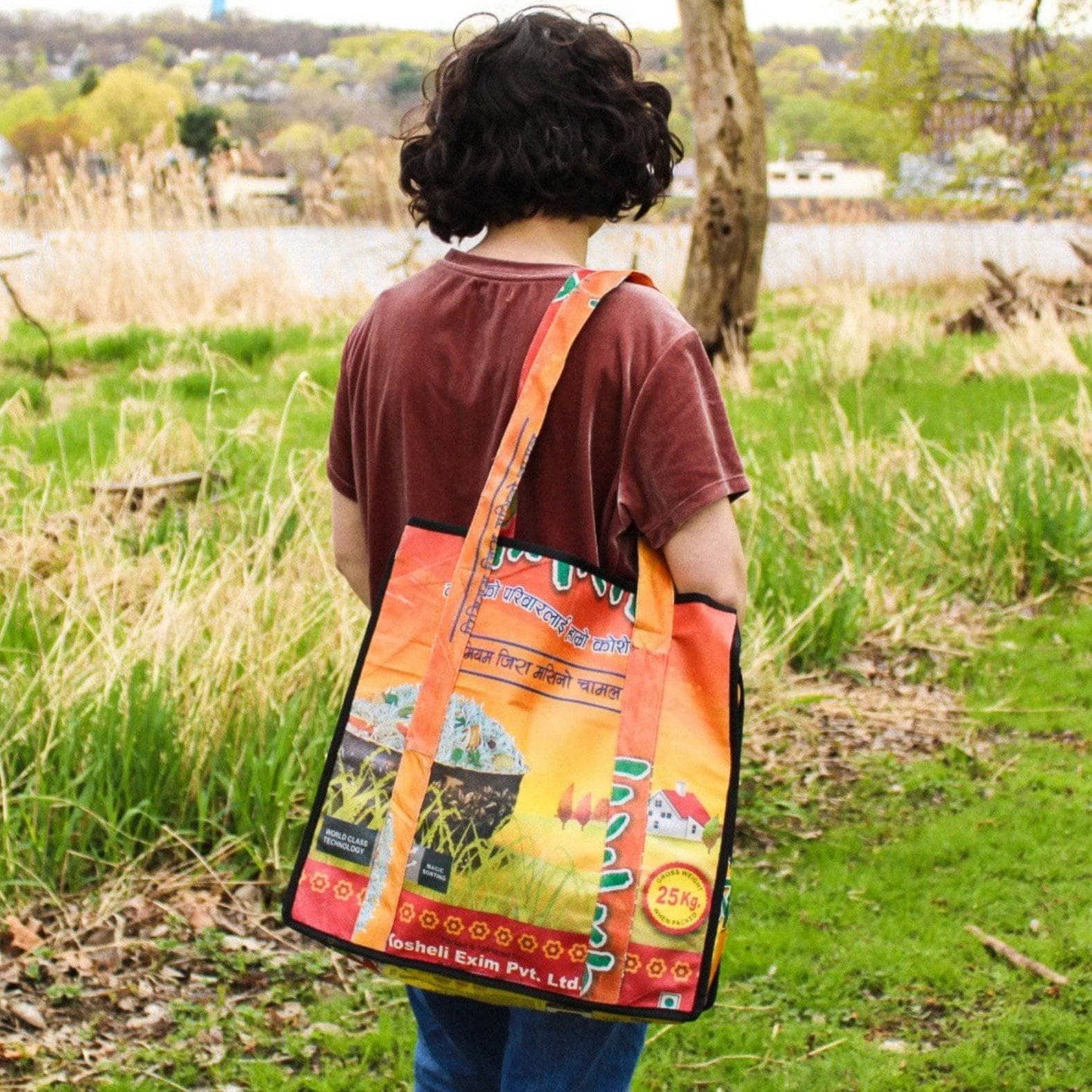 Recycled rice tote bag being carried by model in a grassy field.