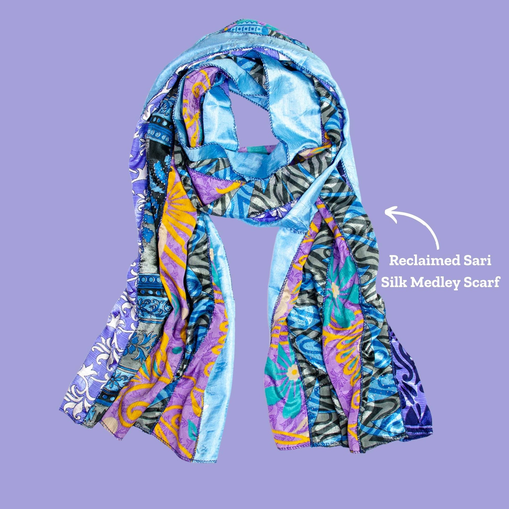 Blue Medley scarf on a purple background. An arrow points to the scarf and reads Reclaimed Sari Silk Medley Scarf. 