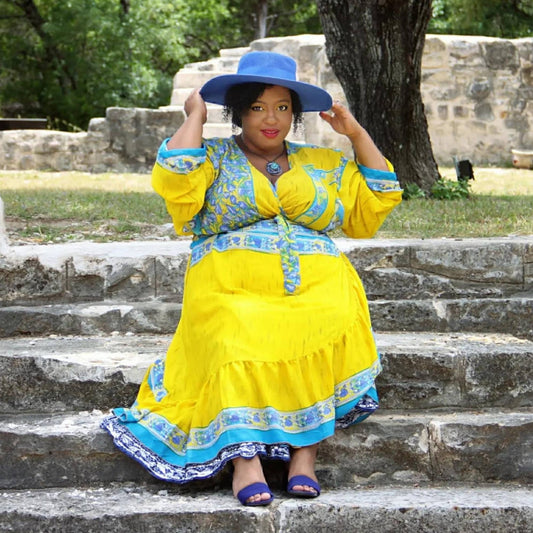 A Model sitting on steps wearing a Yellow and Light Blue Floral Sari Wrap Dress.