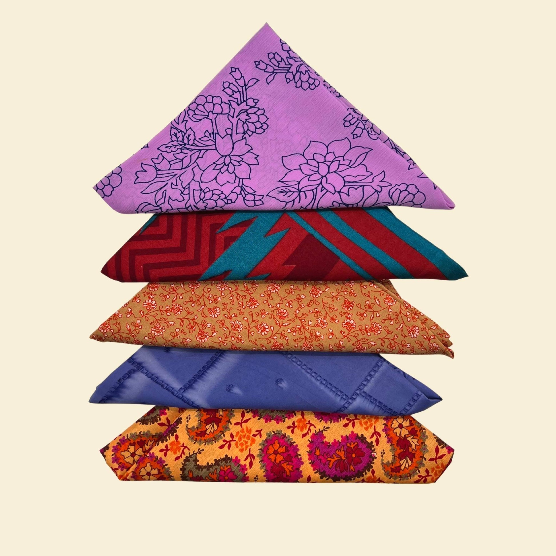 Five Furoshiki folded in triangles on a cream backdrop. 
