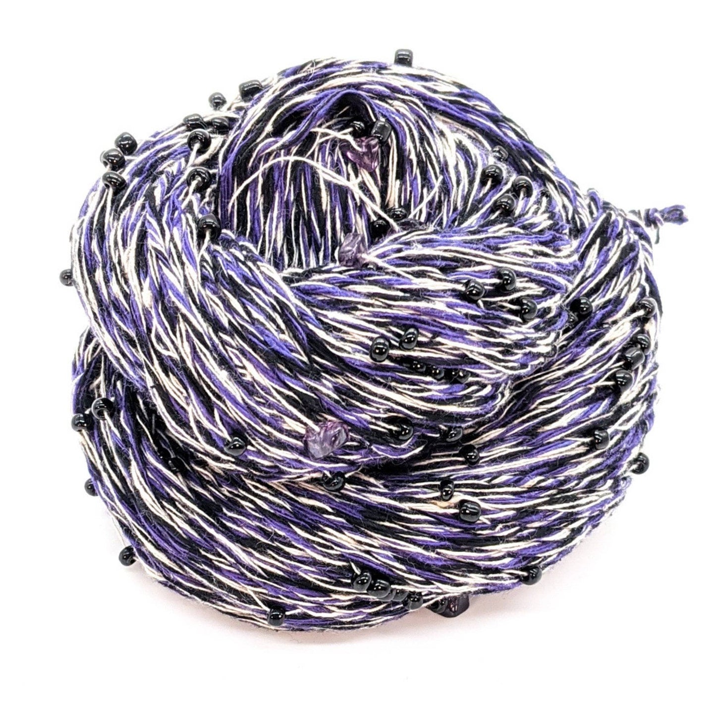 A skein of purple, black and white beaded yarn on a white background