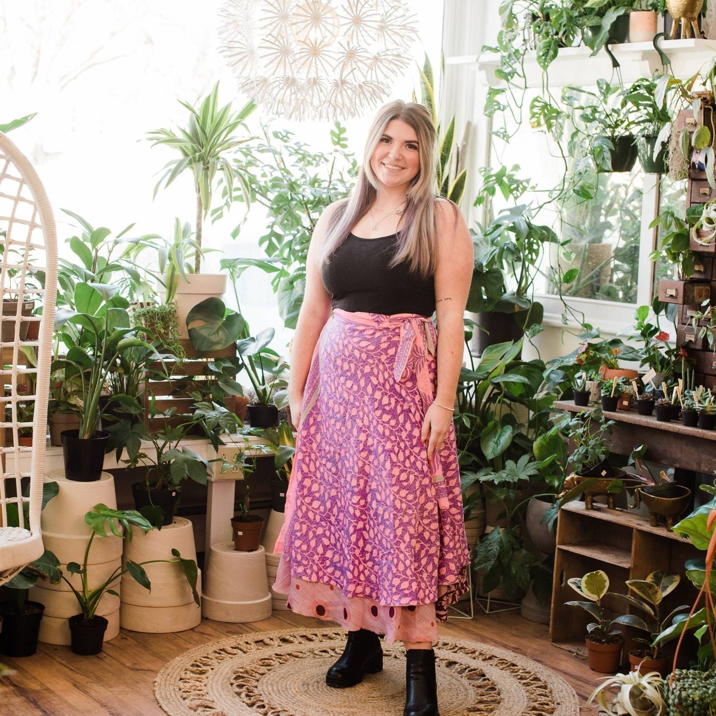 Model wearing a one of a kind pink ankle sari wrap skirt with potted plants in the background.