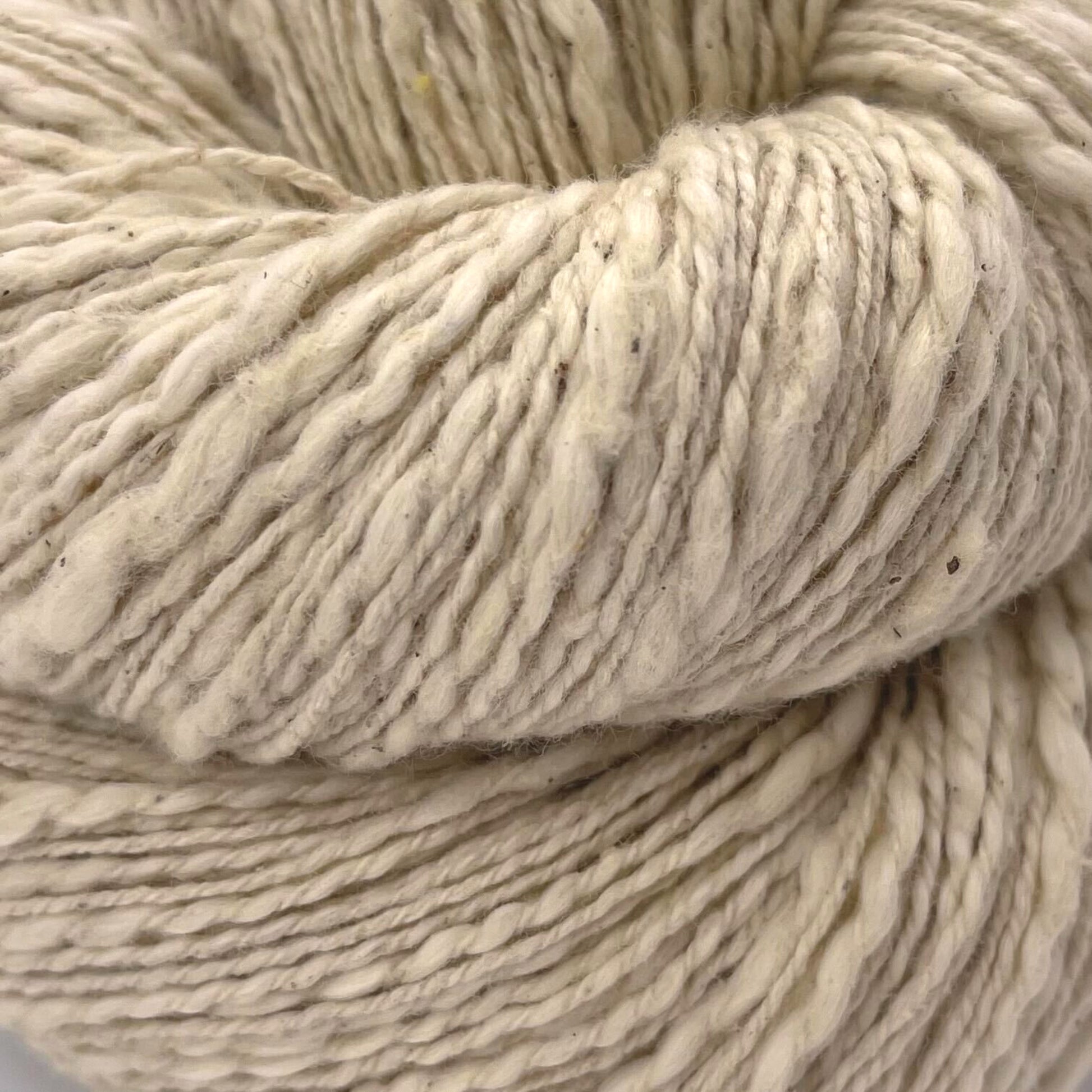 A close up of a skein of white/ undyed cotton yarn on a white background