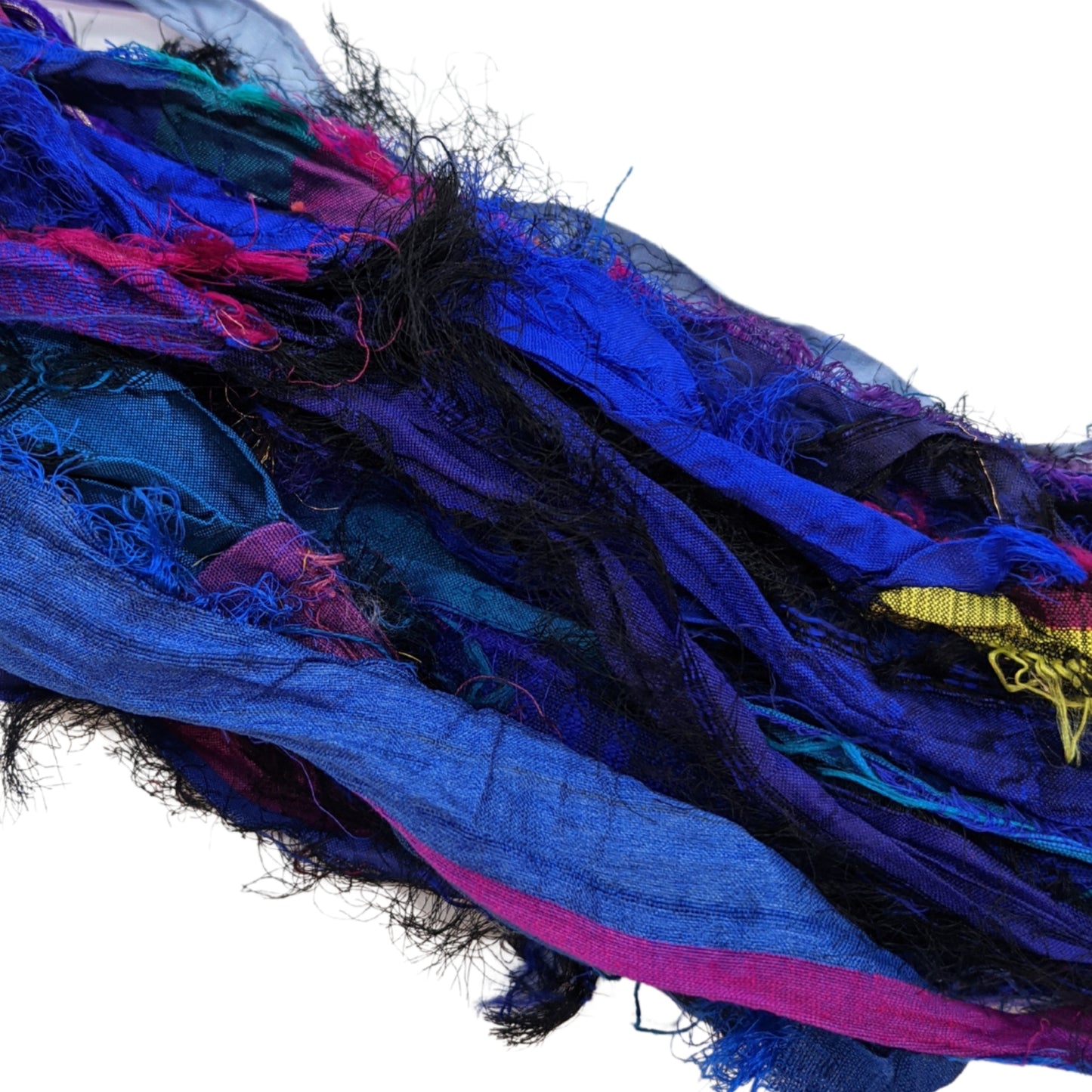 An up closer view of the Indigo sari silk ribbon on a white background. The Indigo includes rich plum purples and blues to blacks and pinks with hints of gold.