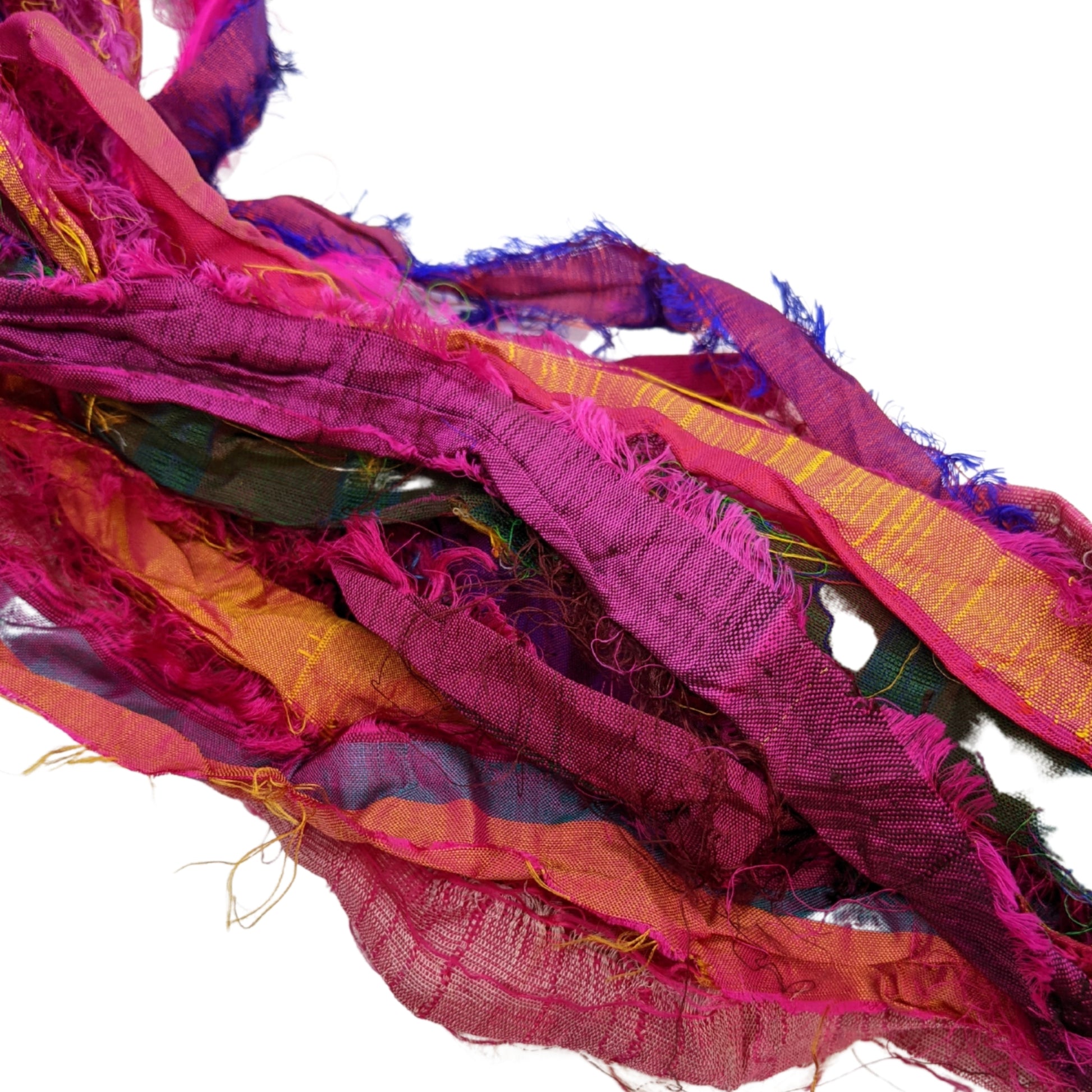 Magenta Sari Silk Ribbon laying on a white background to show the textures and multiple colors inside. Bright pinks and warm reds and oranges.