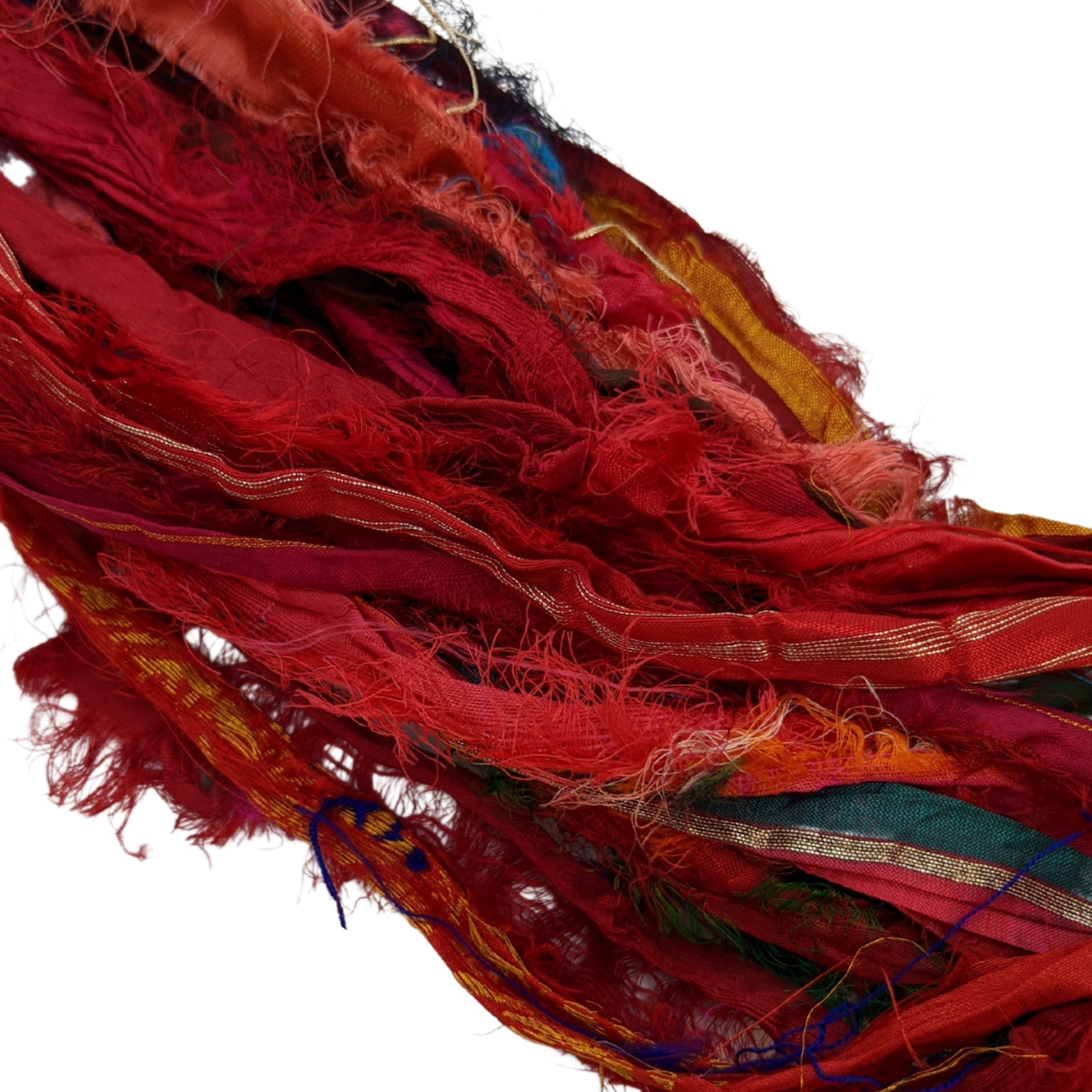 The Red Sari Silk Ribbon laying on a white background. This ribbon includes royal reds and warmer maroons. 