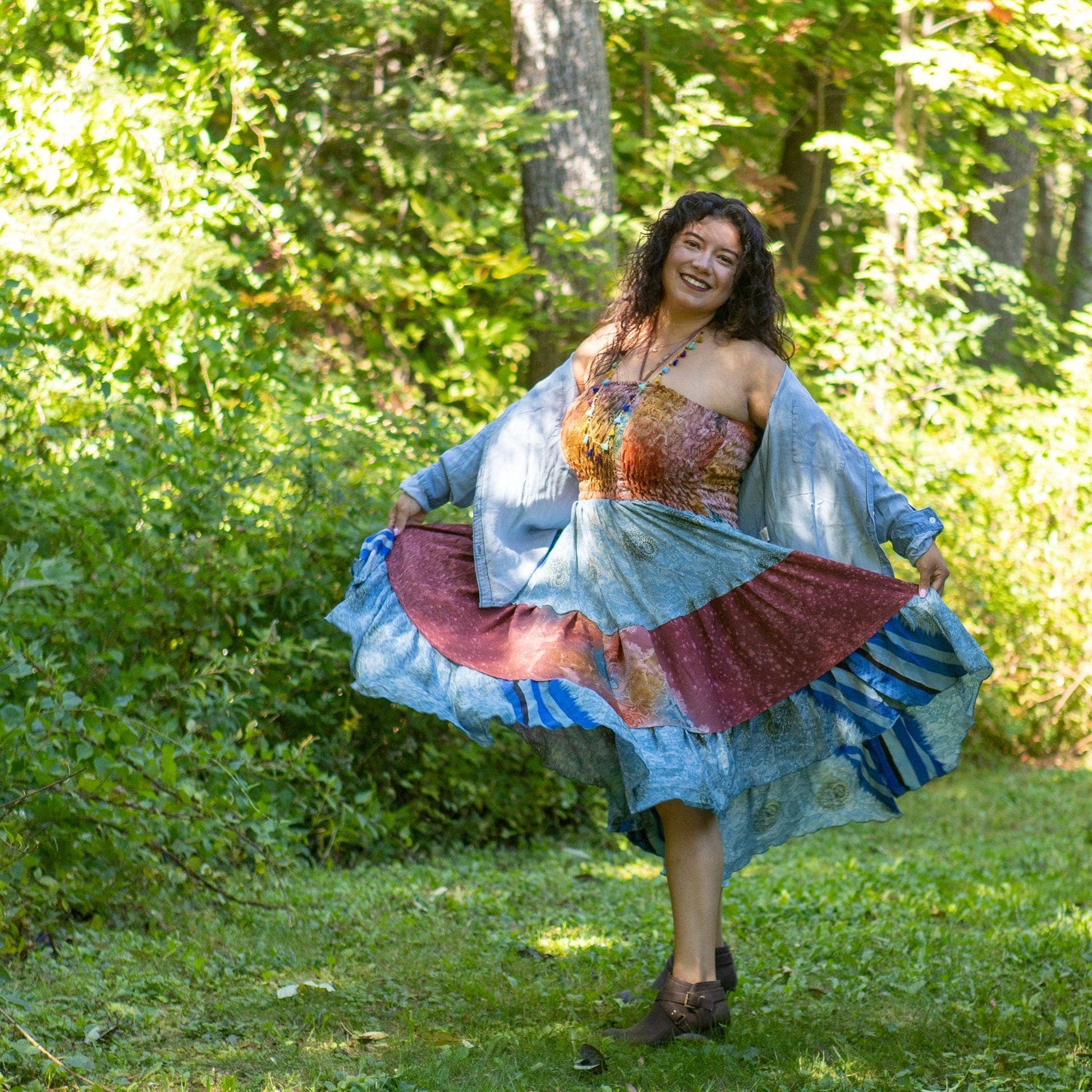 Lady showing the pattern of her Sedona patchwork skirt while standing in the woods with greenery in the background.