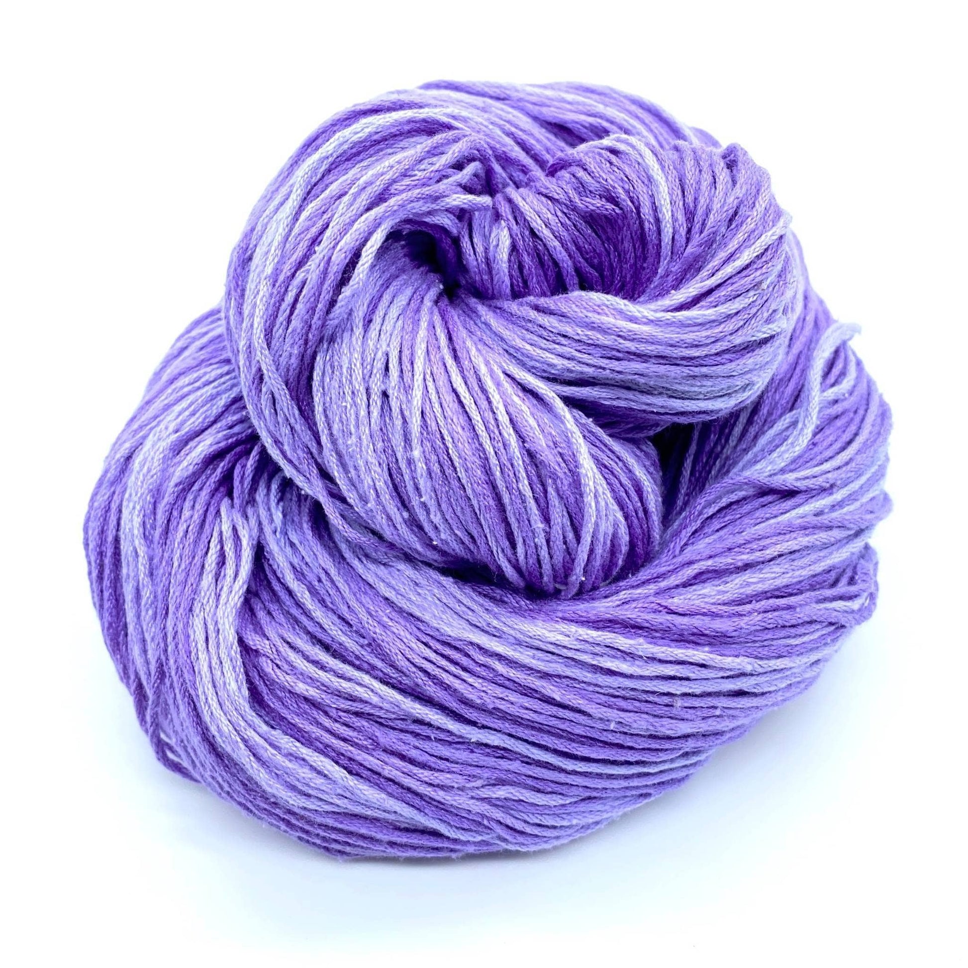 birds nested hank of mulberry silk fingering weight yarn in the colorway lavender fields (light and medium lilac variegated) in front of a white background.