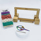 Mini loom kit for weaving with all items showing in front of a white background.